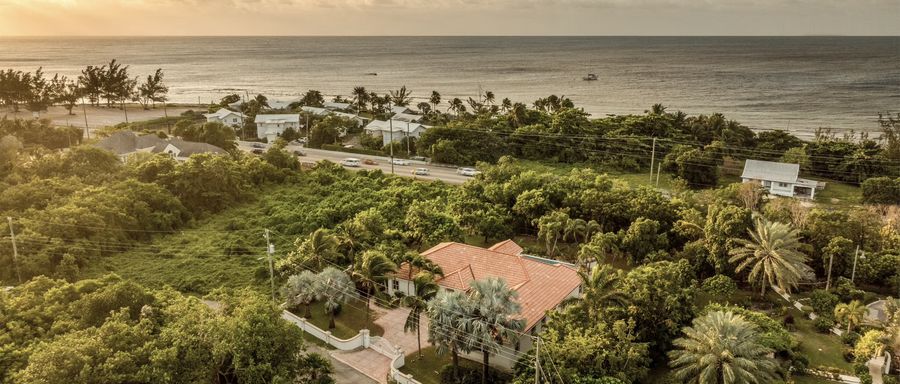 Aerial view of homes among trees along the Grand Cayman coastline at sunset